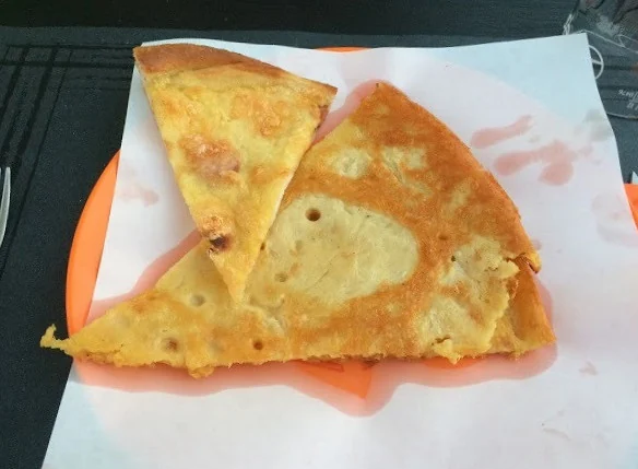 Due fette dorate di calda calda di ceci appoggiate su un foglio di carta arancione.